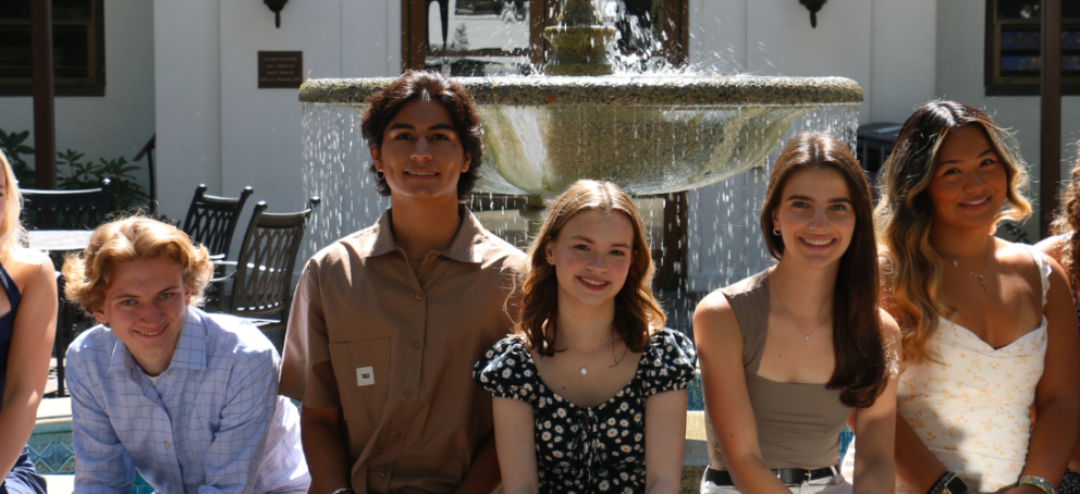 7 people sitting in front of a fountain